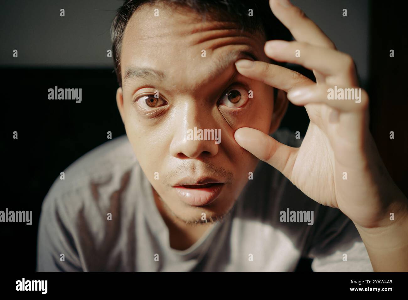 Giovane che apre gli occhi usando le dita Foto Stock