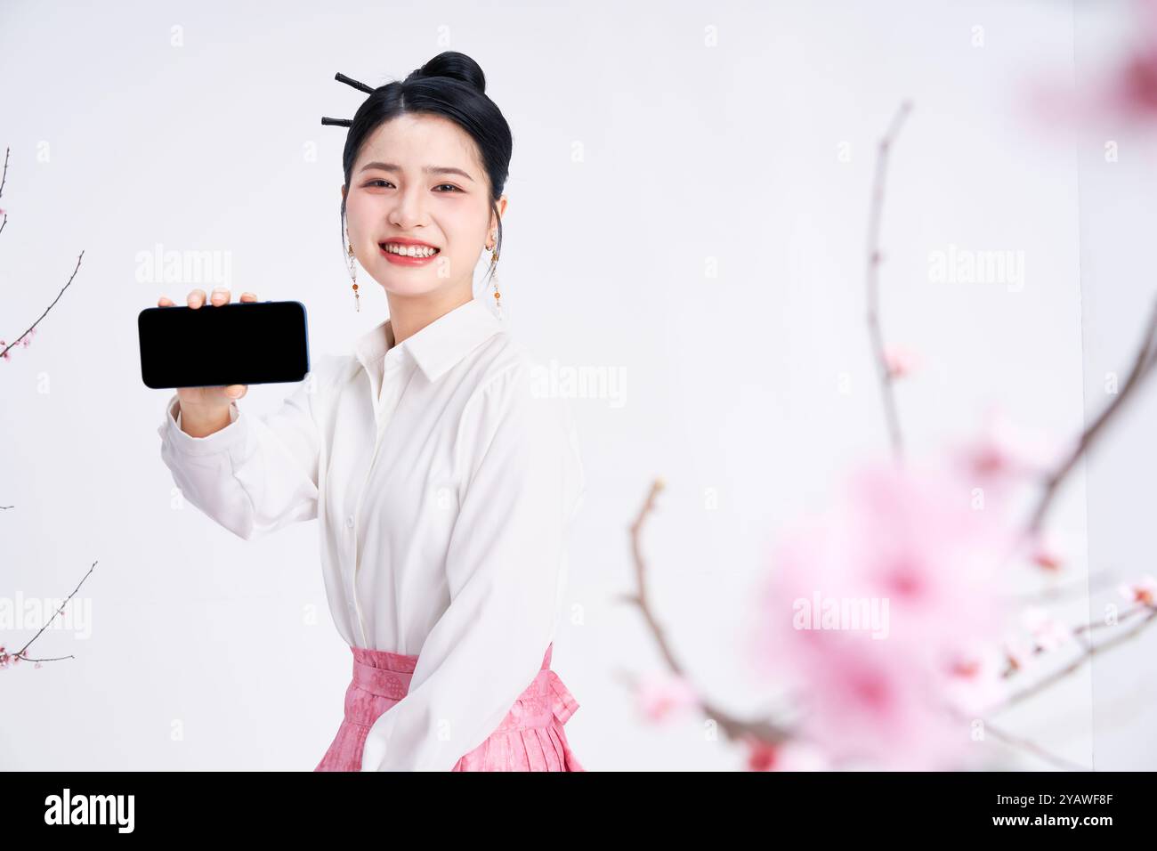 Una giovane donna cinese che tiene un telefono e guarda la macchina fotografica Foto Stock