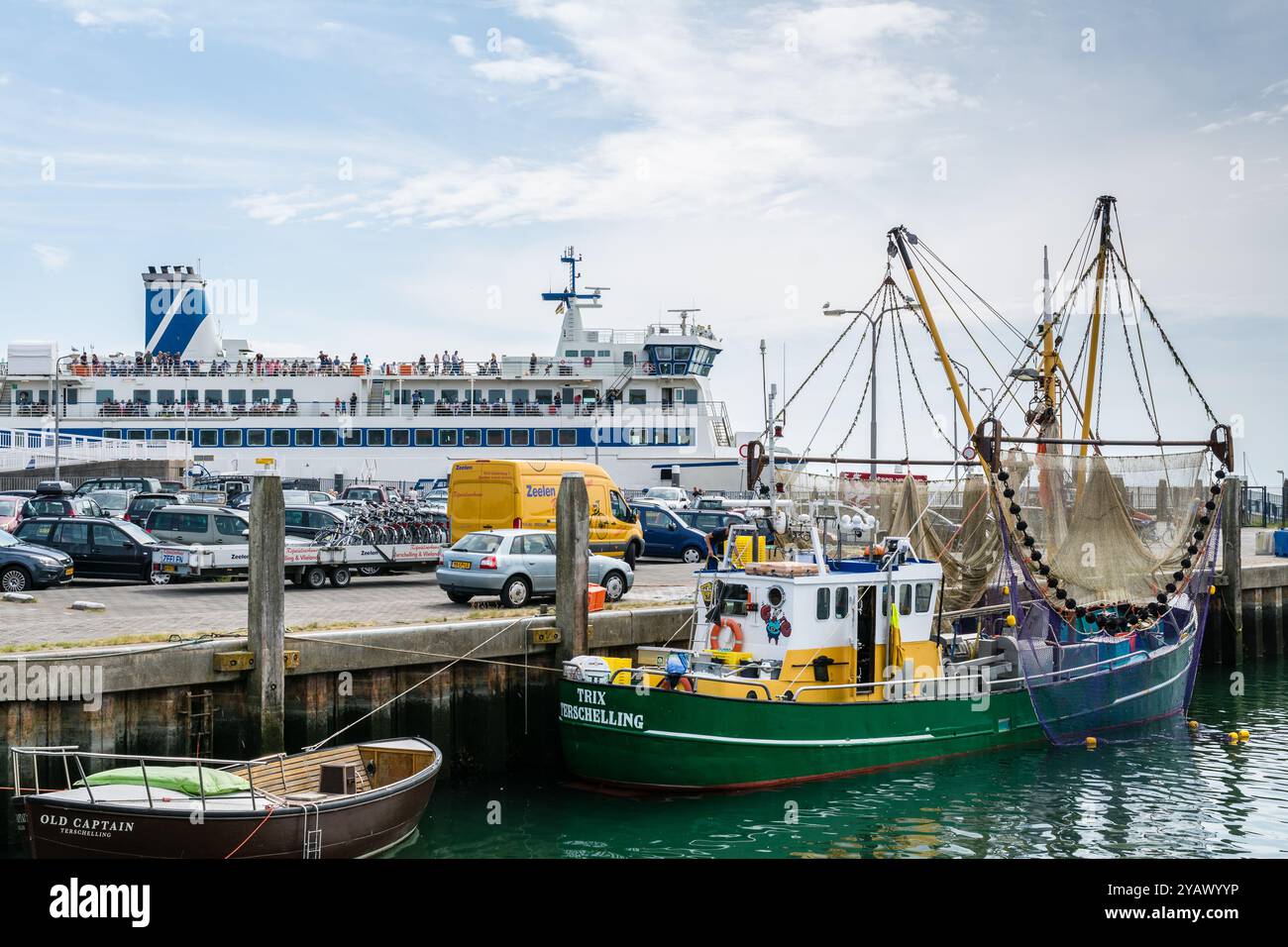 Il traghetto che porta persone e prodotti da e per l'isola di Terschelling nel porto. Con in primo piano una barca da pesca. Foto Stock