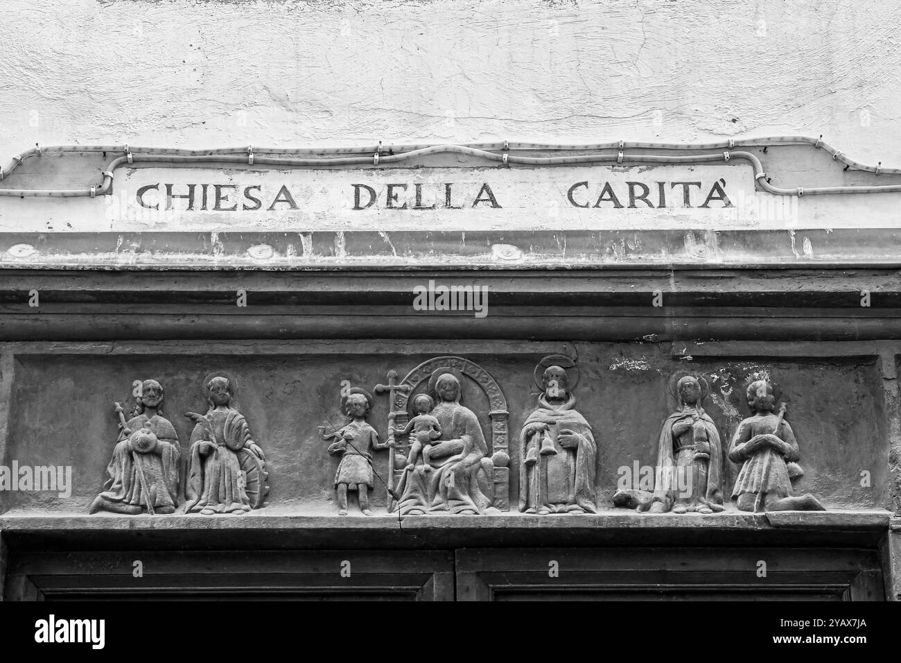 Architrave del portale in ardesia della Chiesa della Carità con bassorilievo della Madonna in trono con bambino circondata da santi, Alassio, Liguria Foto Stock
