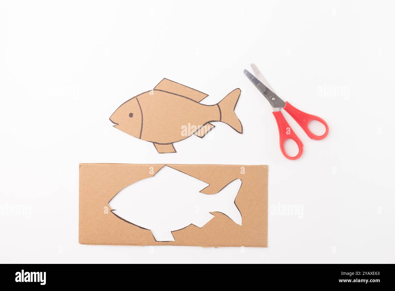 una semplice attività artigianale che comporta il taglio di forme da cartone, utilizzabile per scopi didattici o creativi. tagliare la forma del pesce da solo, a. Foto Stock