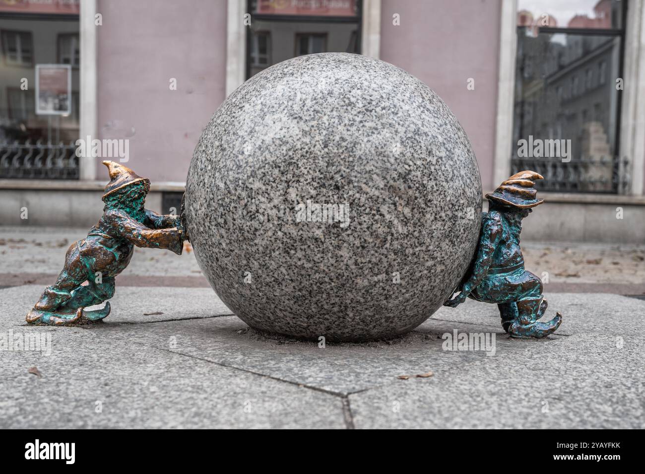 Le statue di gnomi in bronzo sorgono su una strada acciottolata, mostrando arte stravagante in un ambiente urbano pubblico. La cura artigianale dei dettagli aggiunge fascino e carattere Foto Stock