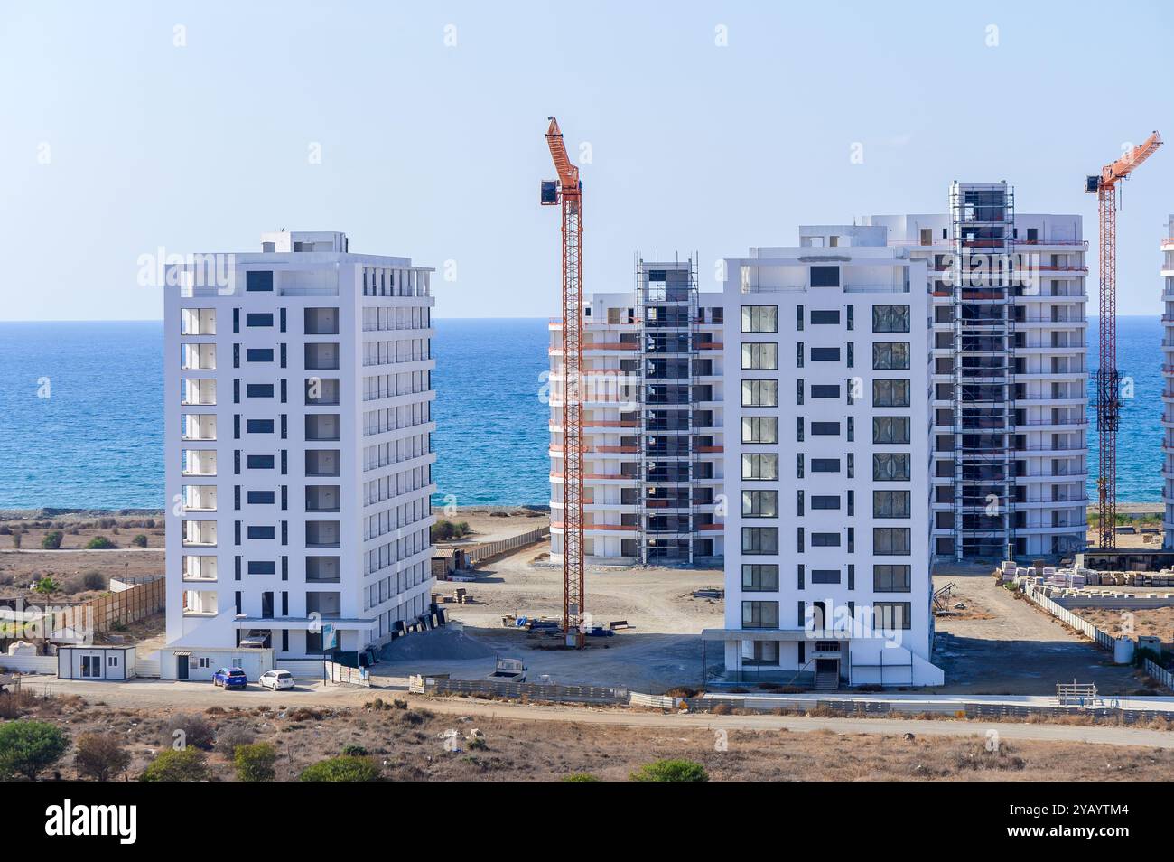 Tra il mare scintillante, gli edifici torreggianti sorgono in uno sviluppo costiero, mostrando architettura moderna su un cielo limpido e uno sfondo panoramico. Foto Stock