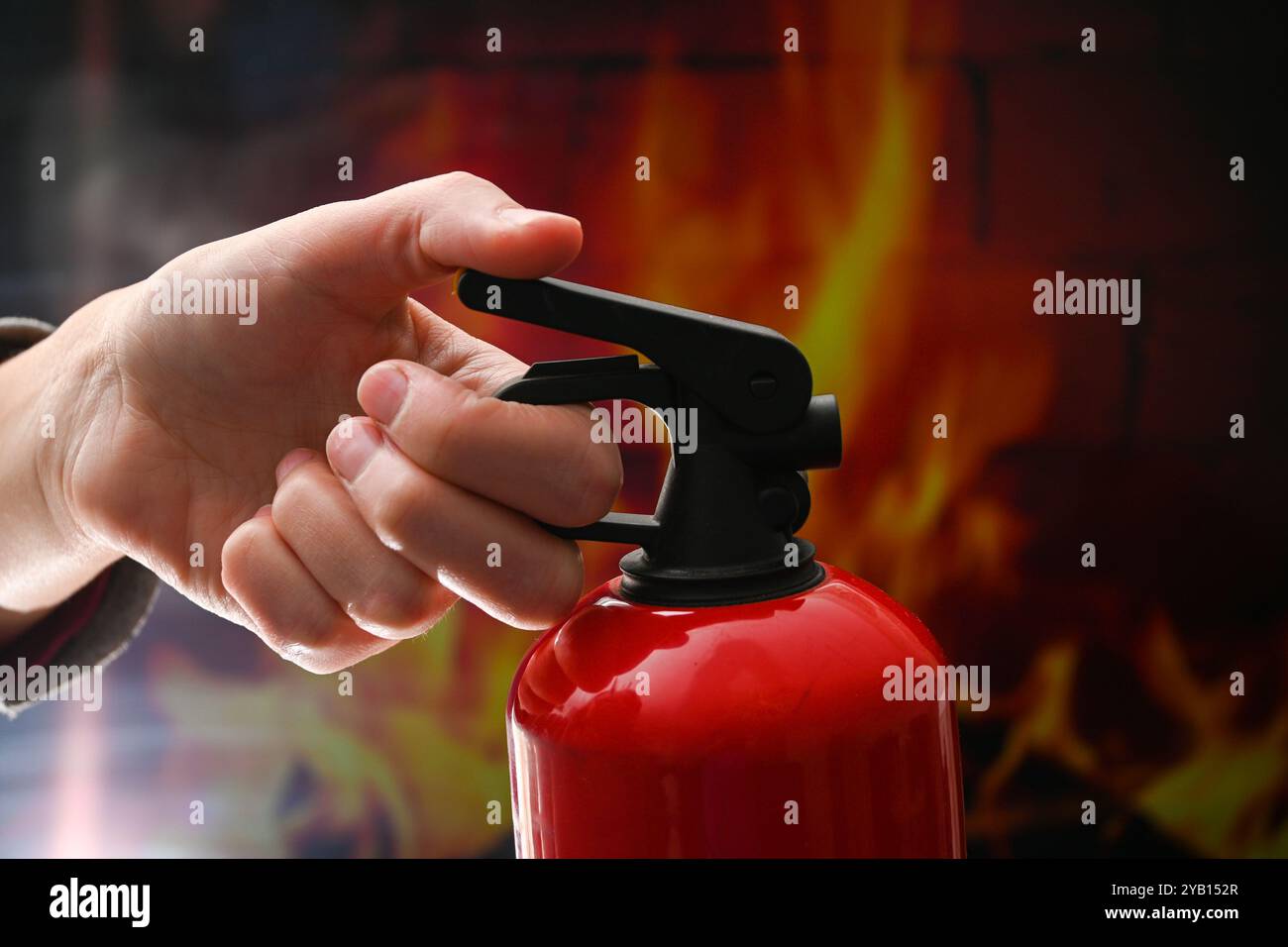 Il vigile del fuoco sta attivando un estintore davanti a un incendio. Foto Stock
