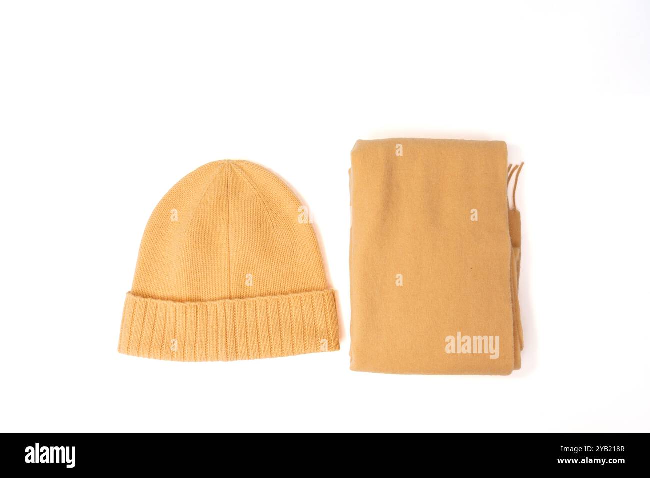 Un cappello e una sciarpa marrone sono disposti su uno sfondo bianco. Il cappello è posizionato sulla parte superiore della sciarpa Foto Stock