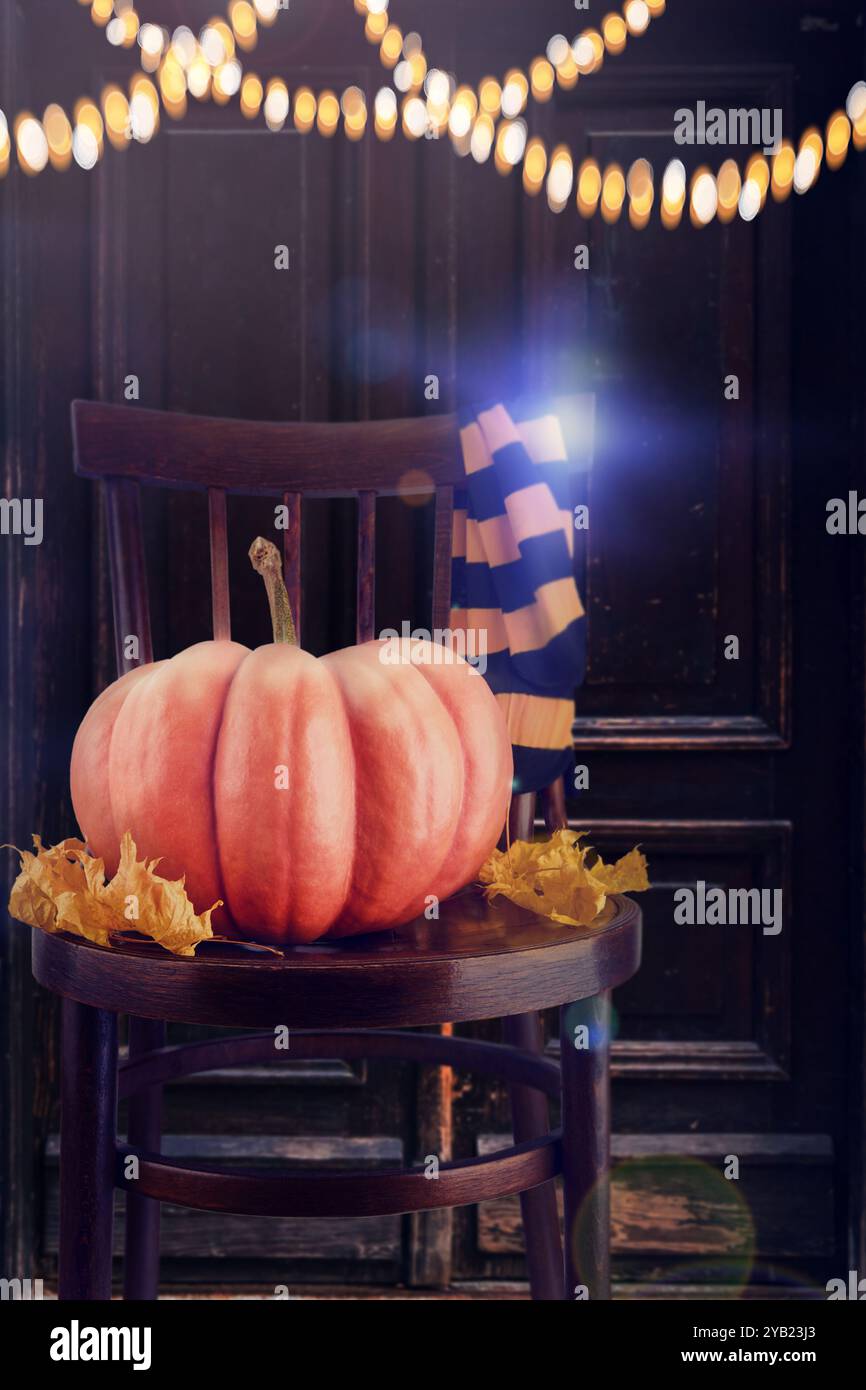 Sfondo di Halloween. Grande zucca con foglie di acero secco, calze a righe nere e arancioni per feste su una vecchia sedia retrò sullo sfondo delle vecchie porte Foto Stock
