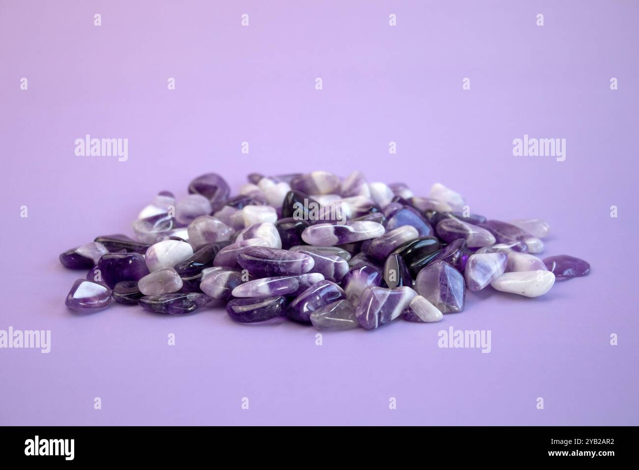 set di varie pietre minerali naturali ametista e pietre preziose su sfondo viola, vista dall'alto parzialmente messa a fuoco Foto Stock