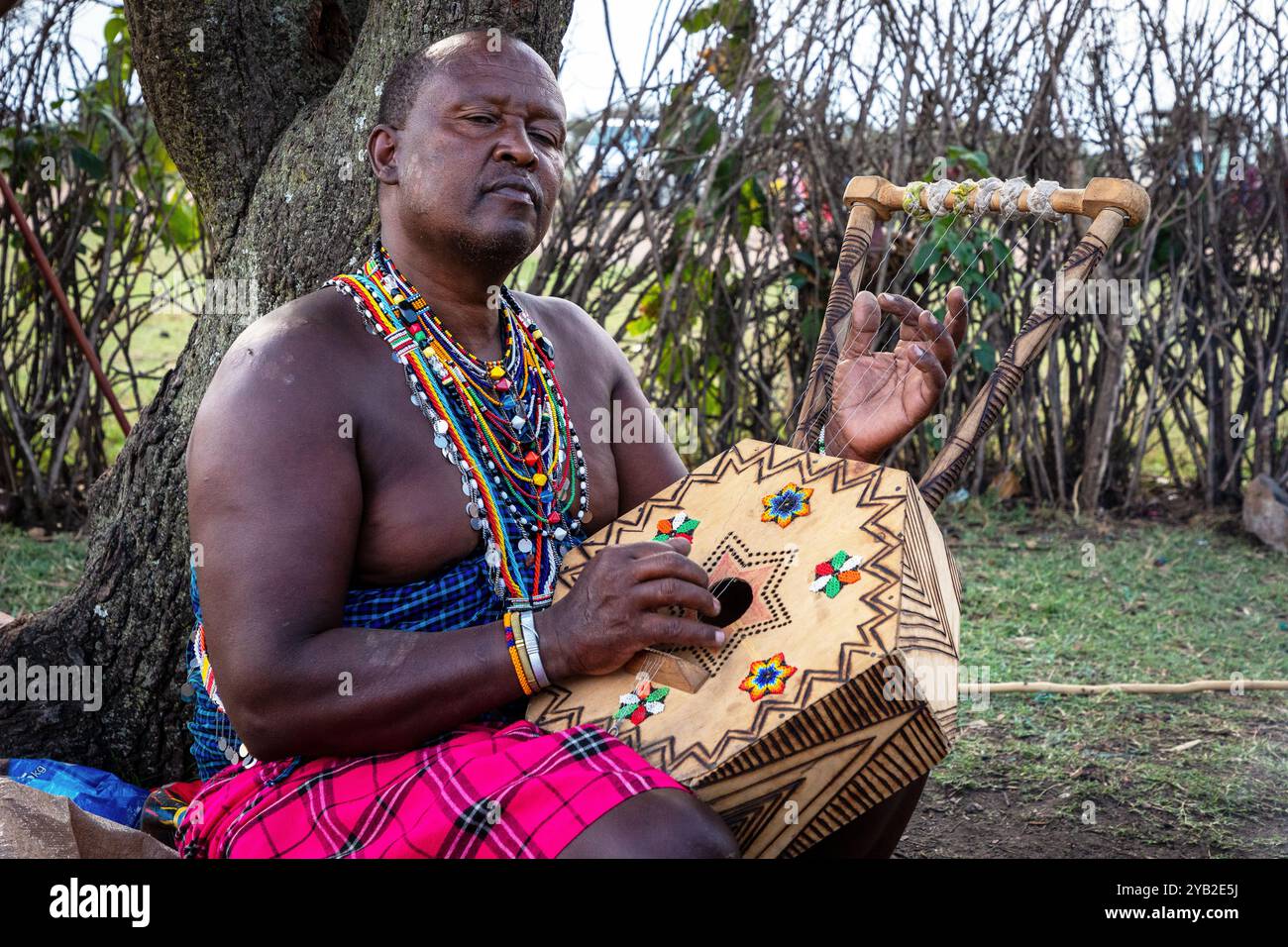 Uomo Masai che suona una tradizionale litunga ornata, strumento musicale a corde del Kenya. Il litungu ha una grande ciotola risuonante fatta di un karai Foto Stock