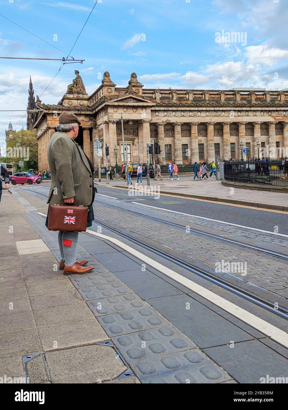 Edimburgo, Scozia, 10 maggio 2024: Uno scozzese, si veste con uniformi tradizionali di kilt e sporrans, si erge in attesa di un tram a Princess Street. Foto Stock