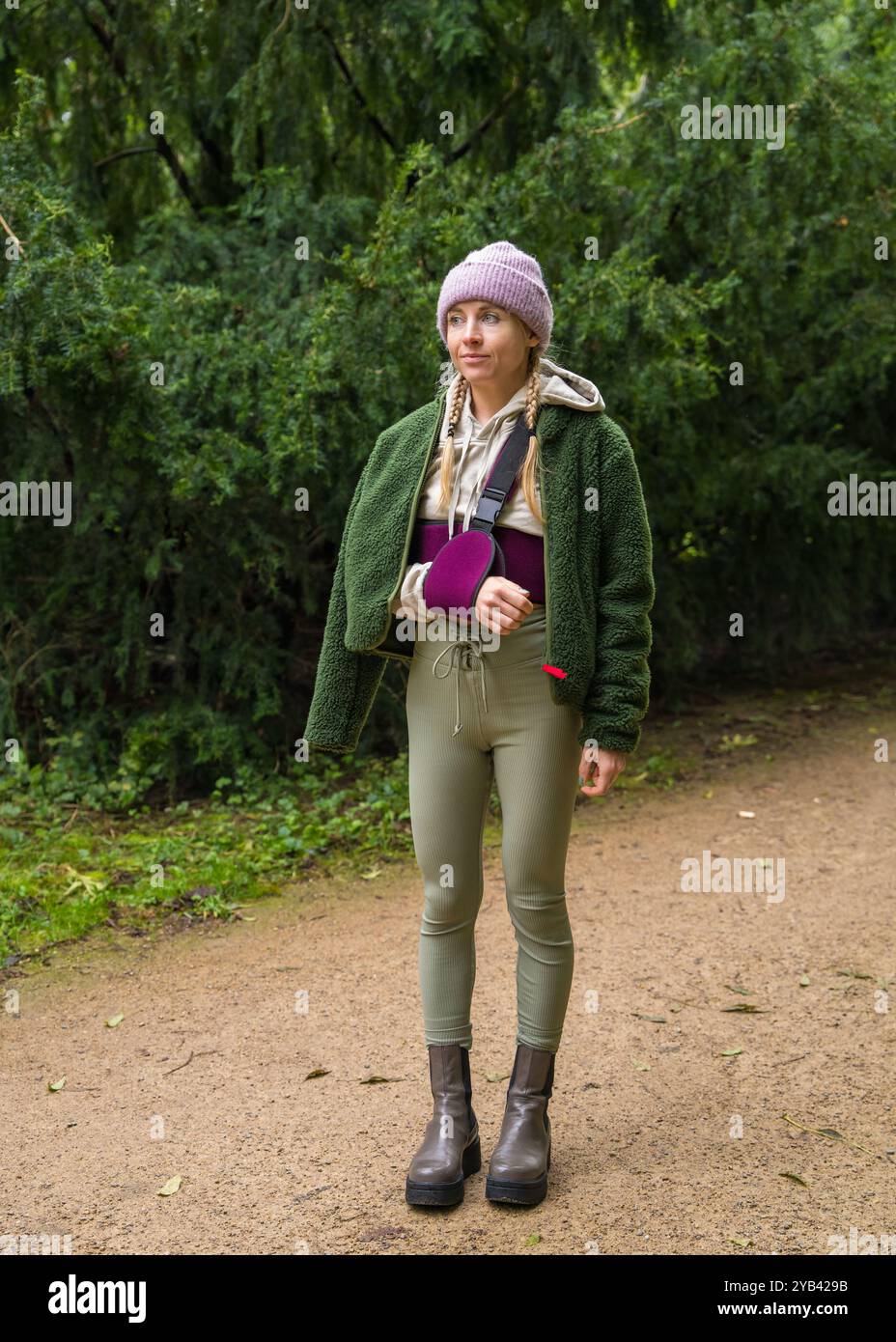 Giovane donna con lesioni al polso che indossa benda e imbracatura per mantenere il braccio ferito immobile, camminando all'aperto. Recupero. Riabilitazione Foto Stock