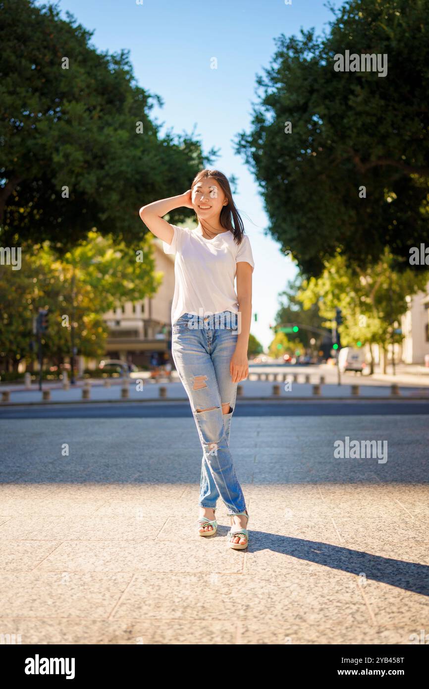 Bella giovane donna asiatica Jeans T-shirt in piedi Downtown Plaza San Jose pomeriggio Sunny Happy Foto Stock