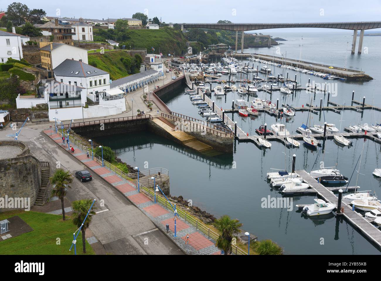 Vista su un porto con numerose barche, architettura circostante e un ponte sullo sfondo in una giornata nuvolosa, Ribadeo, fiume Eo, Galizia, Spagna, EUR Foto Stock