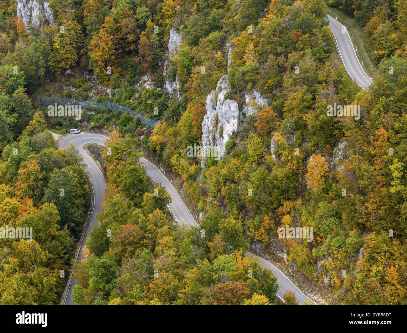 Albe sveva in autunno, Albtrauf con una foresta mista colorata e una strada di campagna tortuosa. Bad Urach, Baden-Wuerttemberg, Germania, Europa Foto Stock