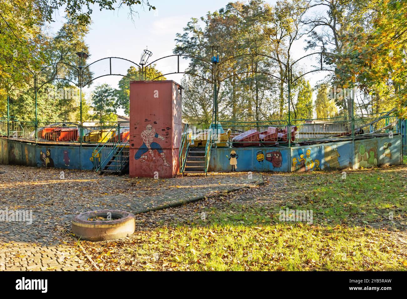 Un vecchio parco divertimenti arrugginito e abbandonato. Un carnevale sbiadito con graffiti a cartoni animati in uno stato di abbandono. Foto Stock