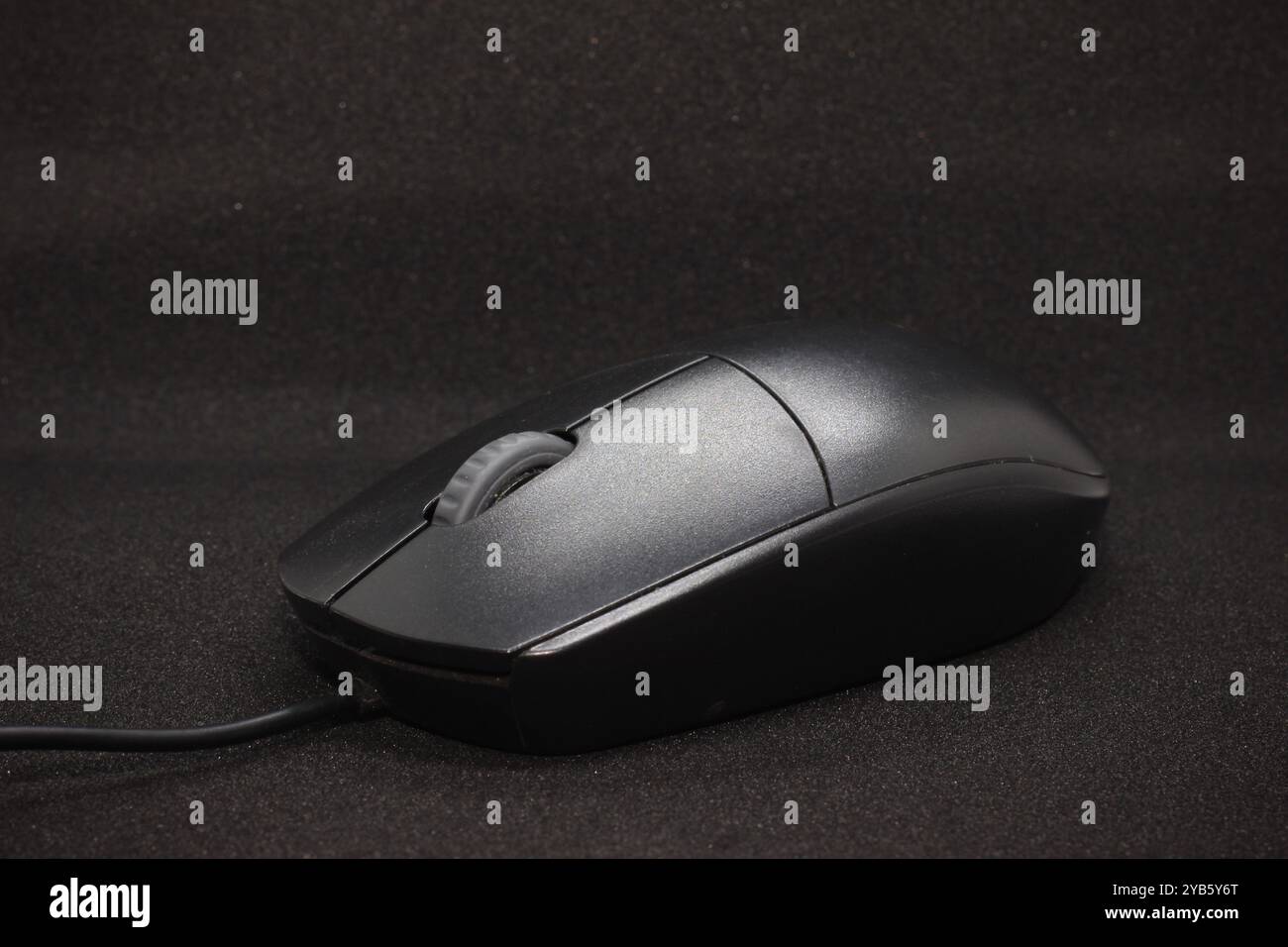 Mouse cablato con due pulsanti e un pulsante di scorrimento centrale, di colore nero, posizionato su uno sfondo nero Foto Stock