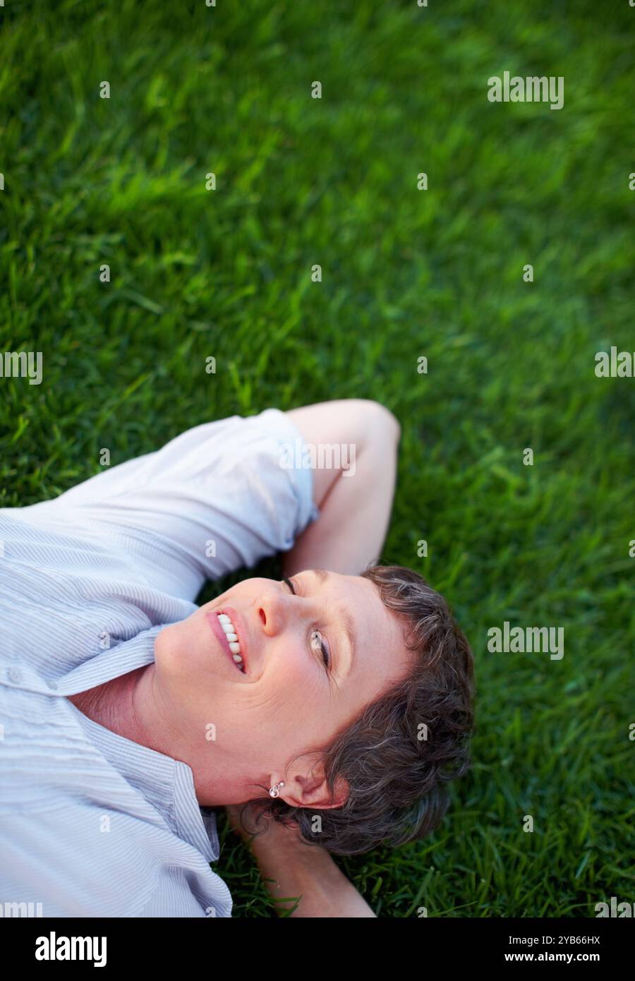 Donna felice, pace e relax su spazio erba per il comfort, zen e salute mentale positiva. Persona matura e rilassante e sorridi nel parco naturale per l'estate Foto Stock