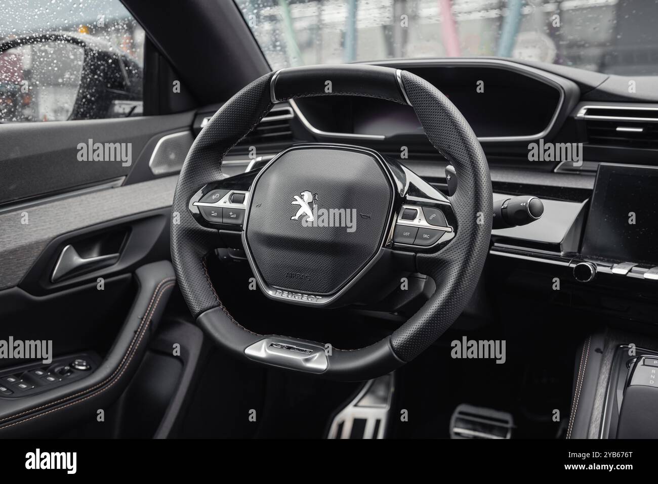 Interno grigio scuro di Peugeot 508. Vista ravvicinata del volante e del cruscotto all'interno dell'elegante berlina Peugeot. Foto Stock