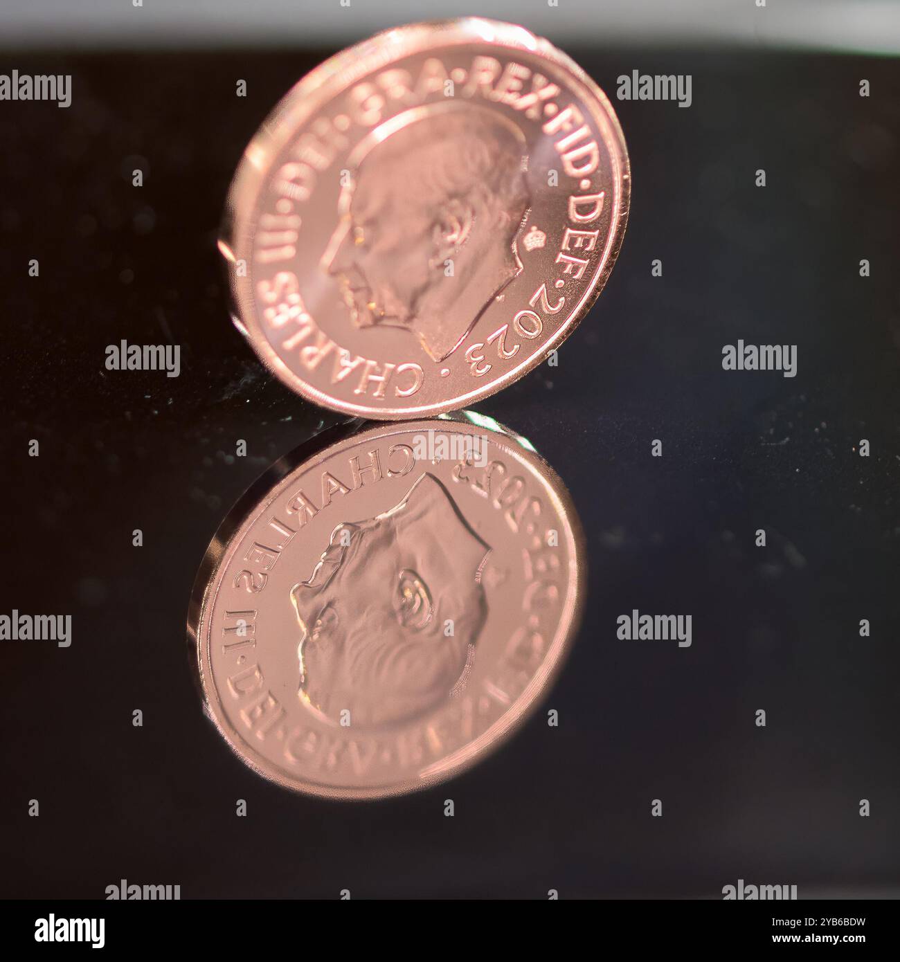 Un pezzo da due pence, la moneta Sterling, sua altezza reale Re Carlo III, in piedi su una superficie nera riflettente, che rispecchia l'immagine Foto Stock