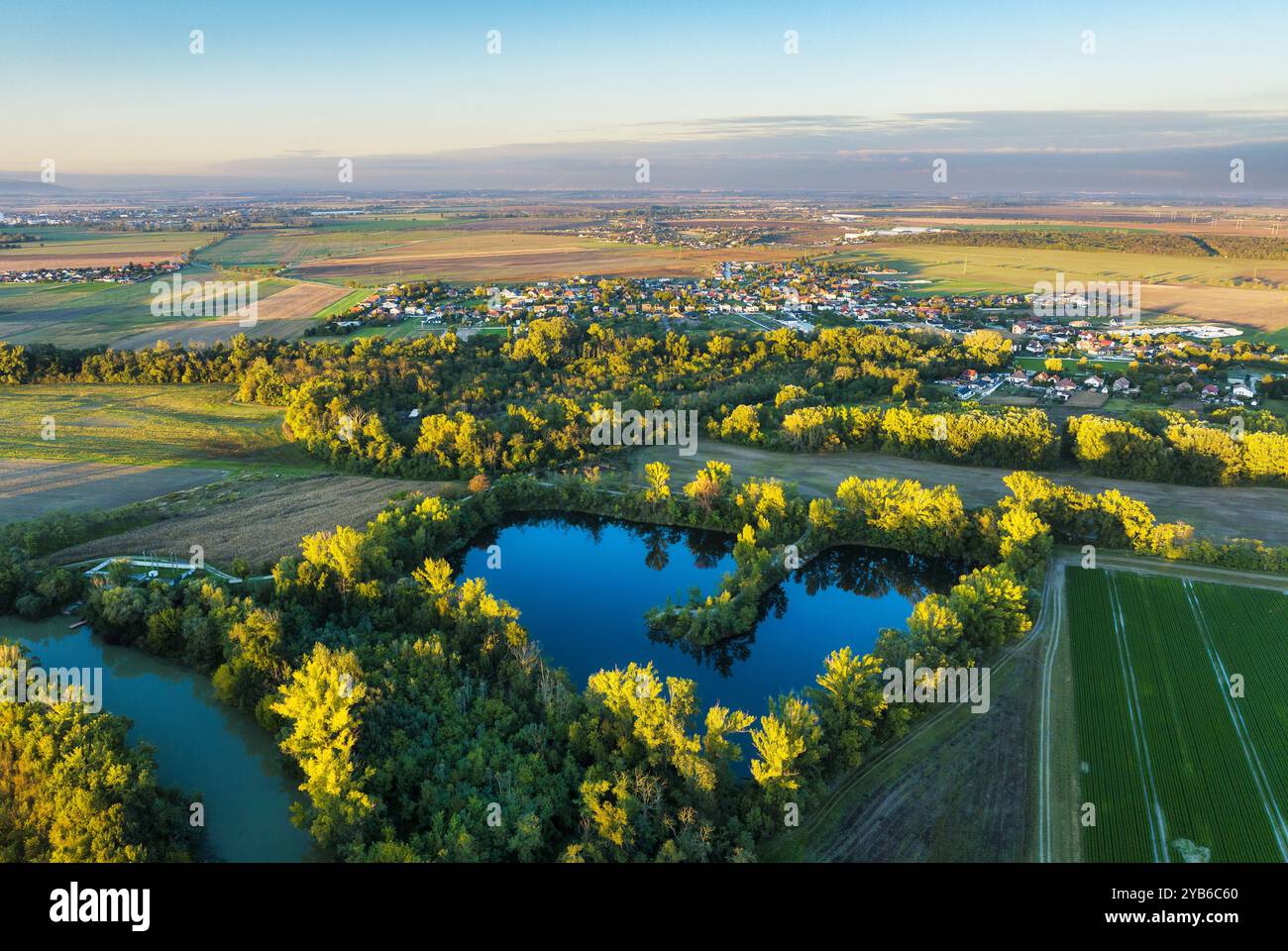 Splendido tramonto sulla Slovacchia con lago, campo, villaggio e foresta. Vista aerea al tramonto. Hruby Sur Foto Stock
