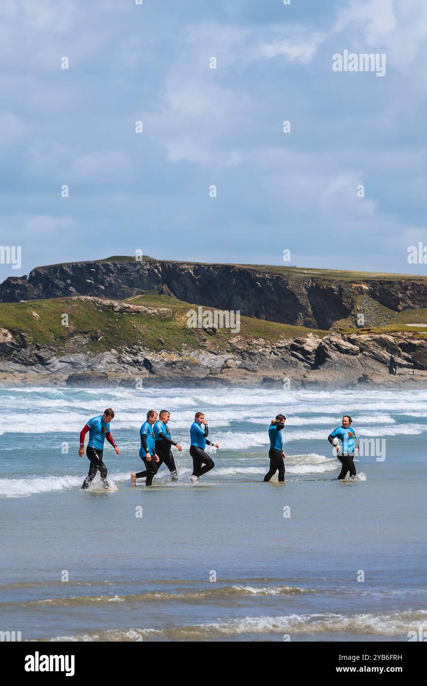Principianti di surf che terminano una lezione di surf con un istruttore del NQY Activity Centre presso Towan Beach a Newquay in Cornovaglia nel Regno Unito. Foto Stock