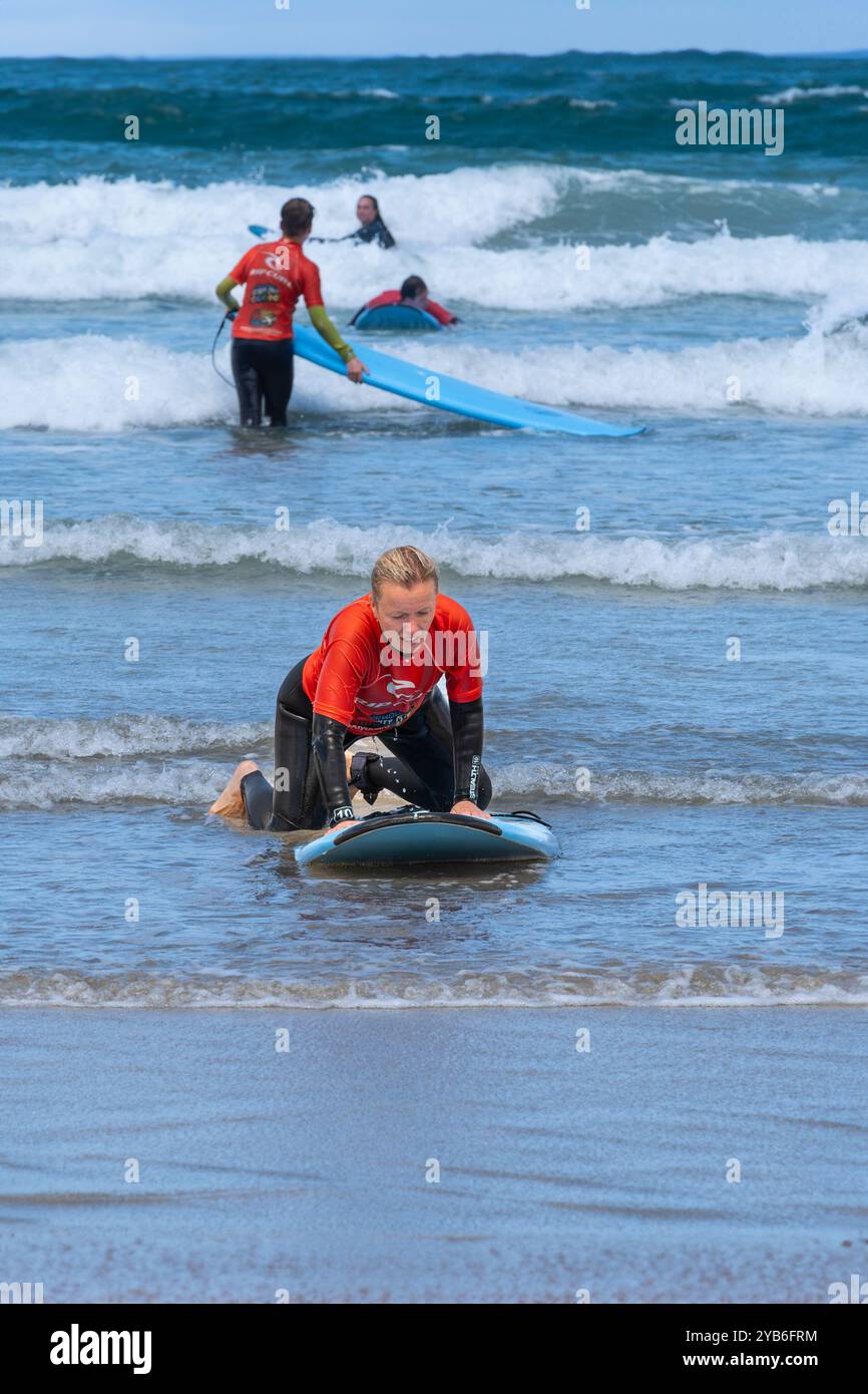 Principianti di surf che tengono una lezione di surf in mare a Towan Beach a Newquay in Cornovaglia nel Regno Unito. Foto Stock