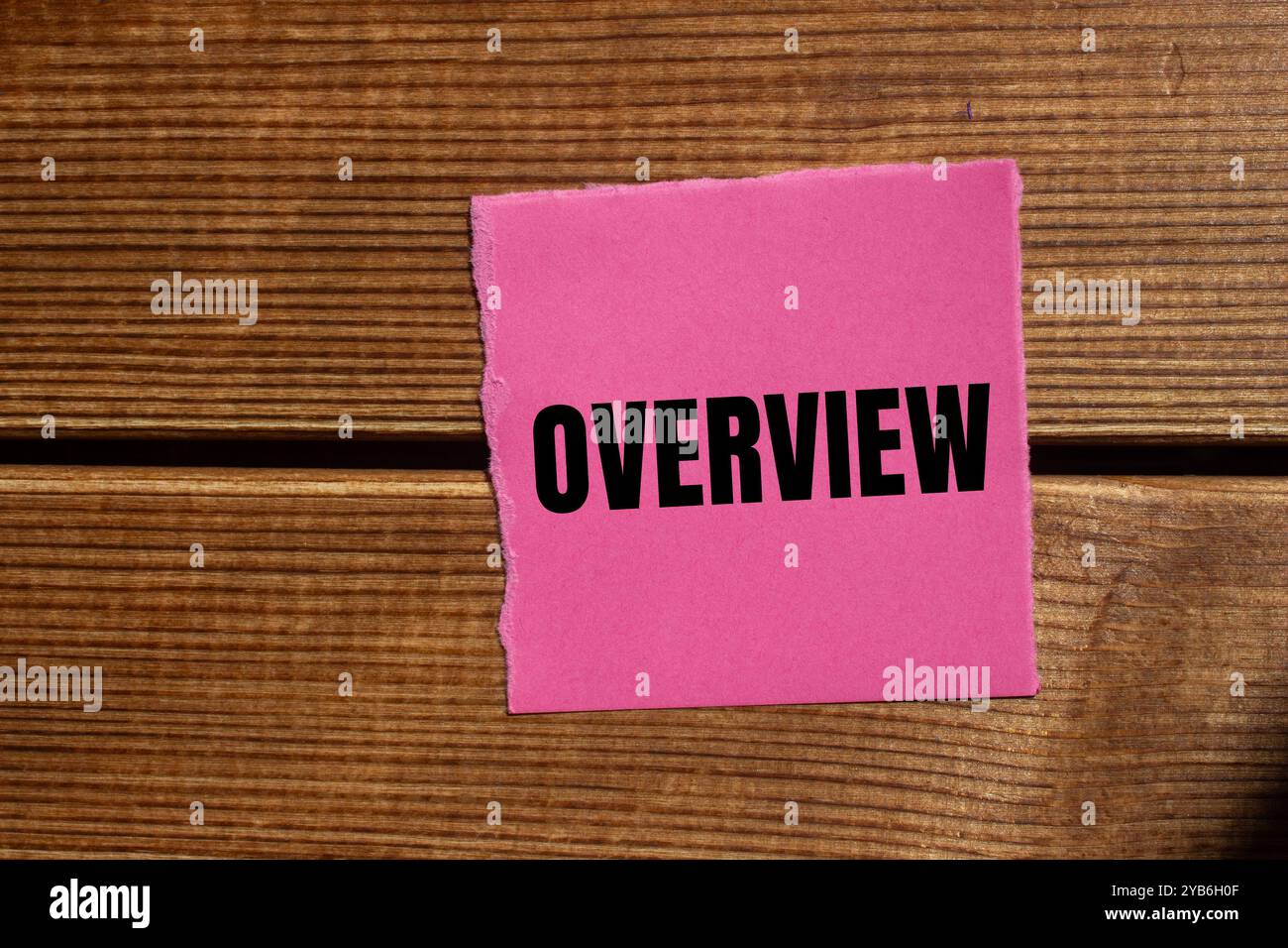 Messaggio generale scritto su un pezzo di carta rosa strappato con sfondo in legno. Simbolo della panoramica concettuale. Copia spazio. Foto Stock