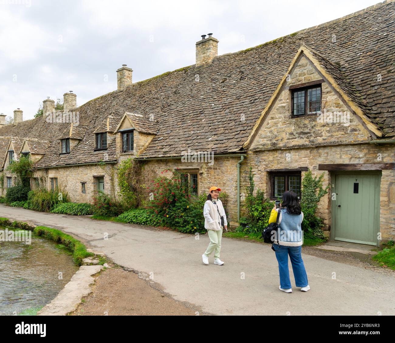 Turisti che visitano i famosi edifici del Cotswold ad Arlington Row, Bibury, Gloucestershire, Inghilterra, Regno Unito Foto Stock