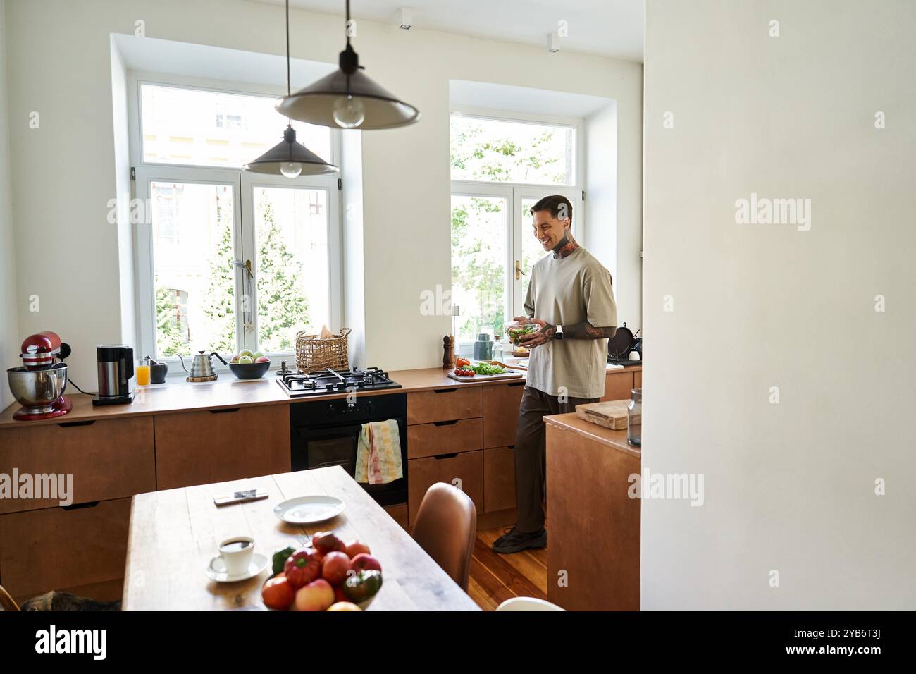 In una cucina elegante, un giovane cucina un pasto con ingredienti freschi, assaporando il momento. Foto Stock