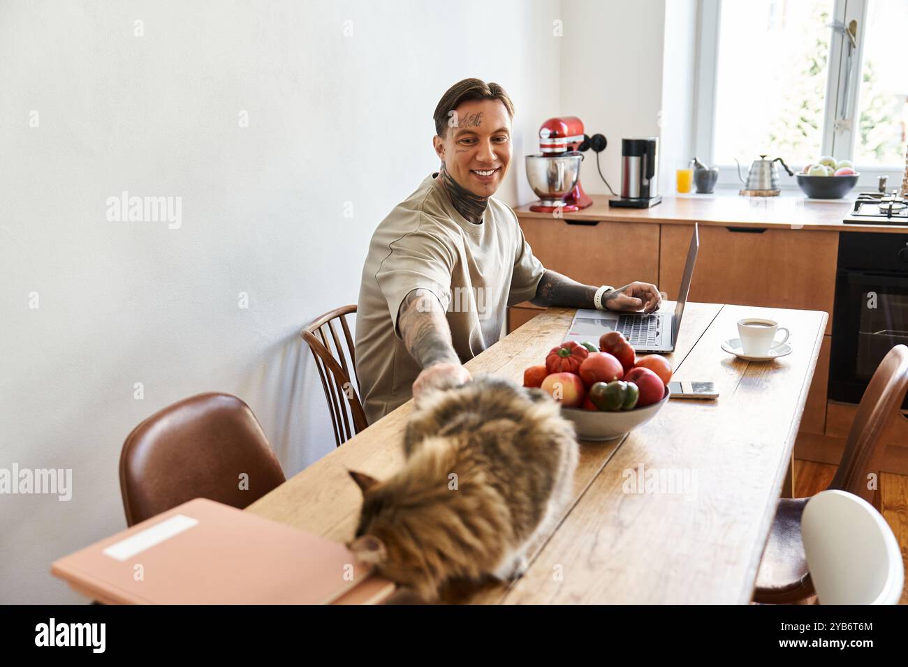 Il giovane si rilassa alla sua tavola, gustando il suo gatto e della frutta fresca. Foto Stock
