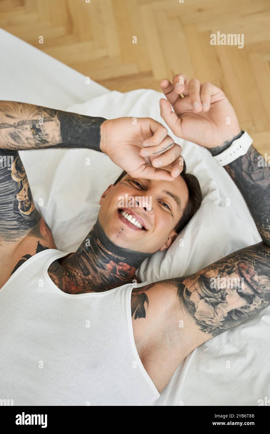Il giovane si rilassa a letto, abbracciando la sua personalità gioiosa. Foto Stock