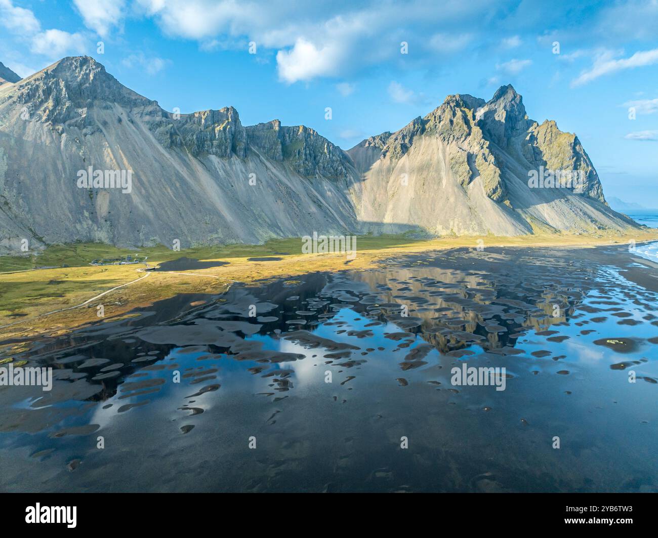 Veduta aerea del Monte Vestrahorn , spiaggia di lava nera, riflessi sull'acqua, Stokksnes, a est di Höfn, fiordi orientali, Islanda Foto Stock