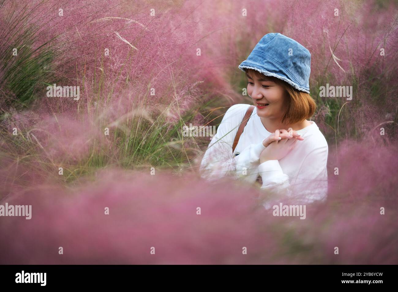 Felice bella giovane donna asiatica circondata da erba di muhly rosa hairawn (muhlenbergia capillaris) Foto Stock