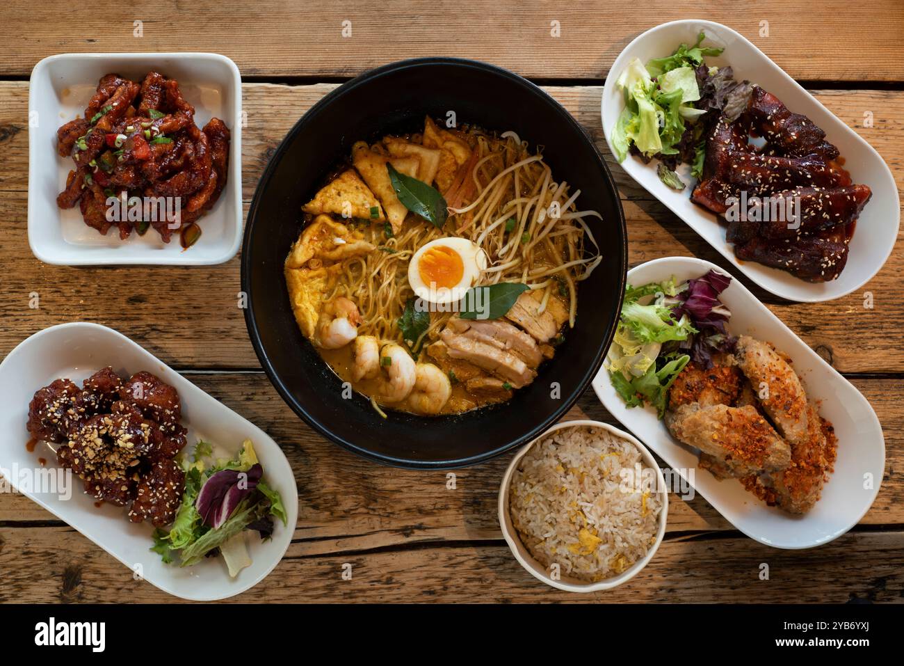 Piatti asiatici selezionati, tra cui Laksa al curry, pollo dolce e acido, ali di pollo al barbecue coreane speziate e kimchi Foto Stock