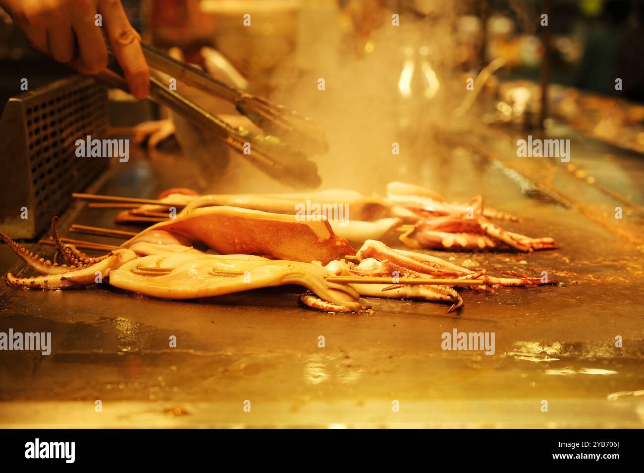 Calamari Teppanyaki. Cuocere a mano i calamari sulla piastra di ferro. Cucina giapponese Foto Stock