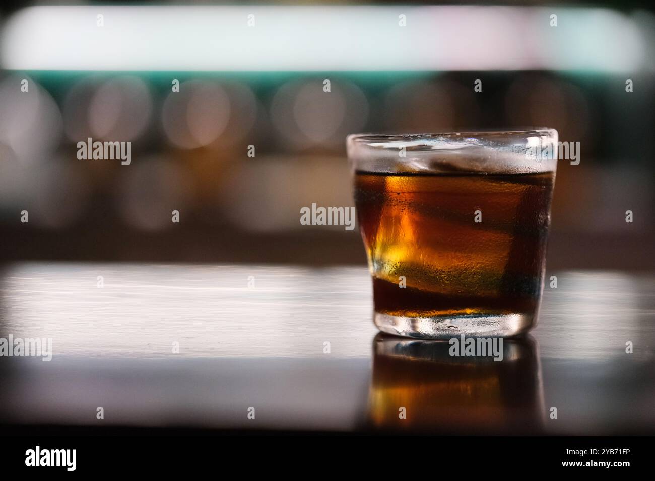 primo piano, un bicchiere di whiskey cocktail al bar con bokeh sfocato di notte Foto Stock