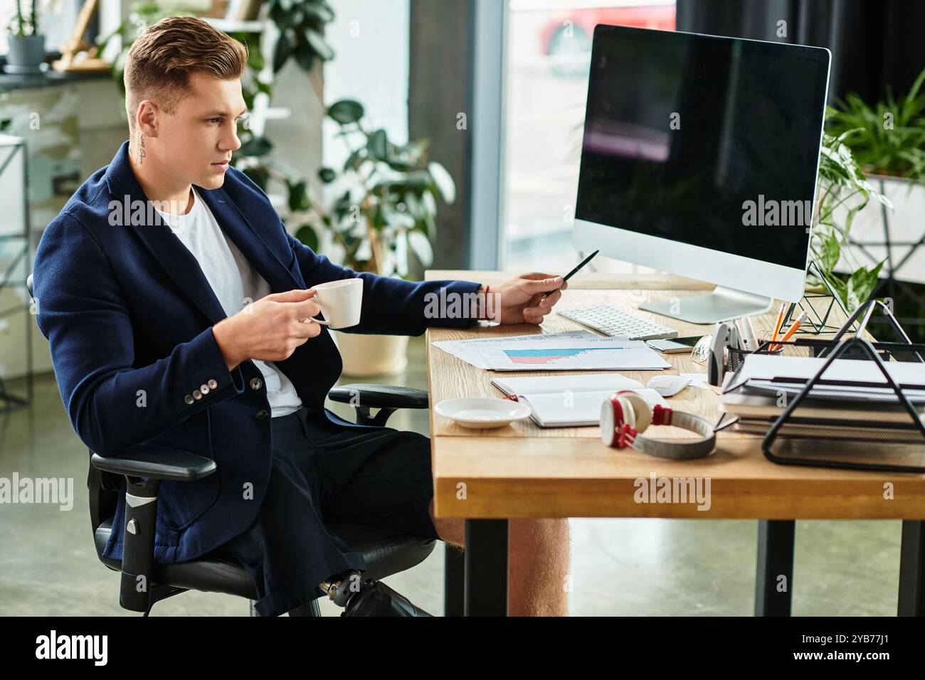 Un uomo d'affari determinato con un arto artificiale lavora diligentemente alla sua scrivania, mostrando l'inclusione sul luogo di lavoro. Foto Stock