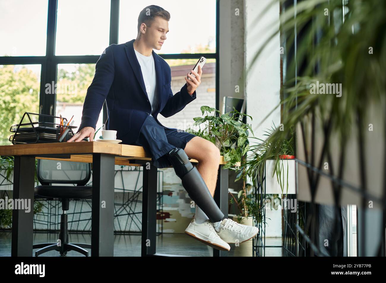 Un giovane e ambizioso uomo d'affari con disabilità si impegna con il suo smartphone mentre è al lavoro. Foto Stock