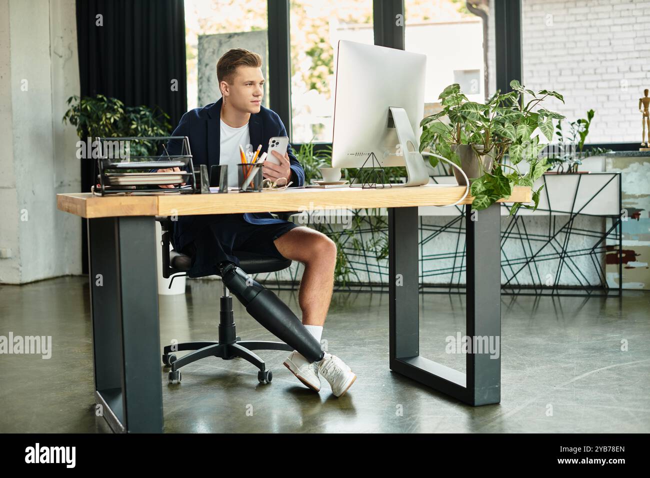 Un giovane professionista con disabilità lavora diligentemente in un ambiente d'ufficio elegante e moderno. Foto Stock