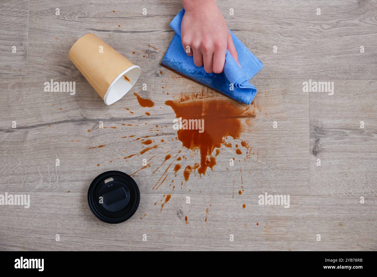La tazza di carta di caffè è caduta su laminato, caffè versato sul pavimento. Foto Stock