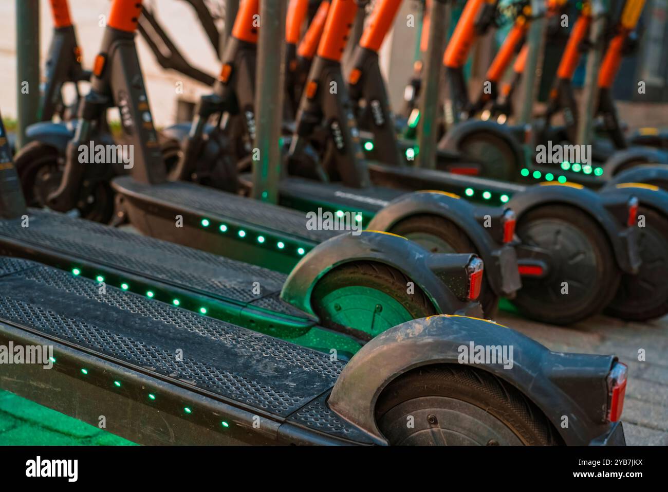 Molti scooter e biciclette nel parcheggio. Noleggio di veicoli elettrici per muoversi in città. Gadget tecnologici e tecnologia moderna in trasposizione Foto Stock
