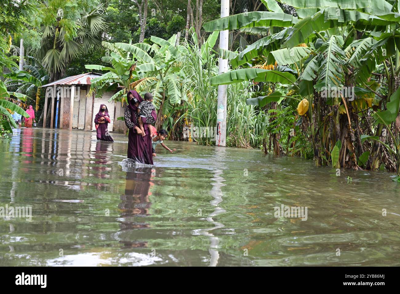 Le persone attraversano le acque alluvionali del distretto di Feni, Bangladesh, il 24 agosto 2024. Foto Stock