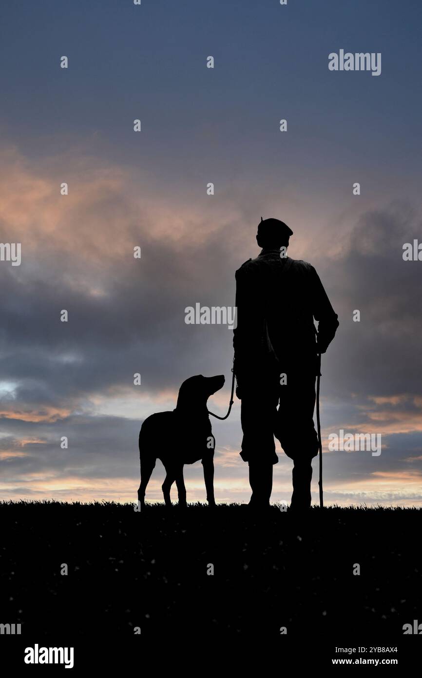 hunter e il suo cane alla fine della giornata, in sihouette Foto Stock