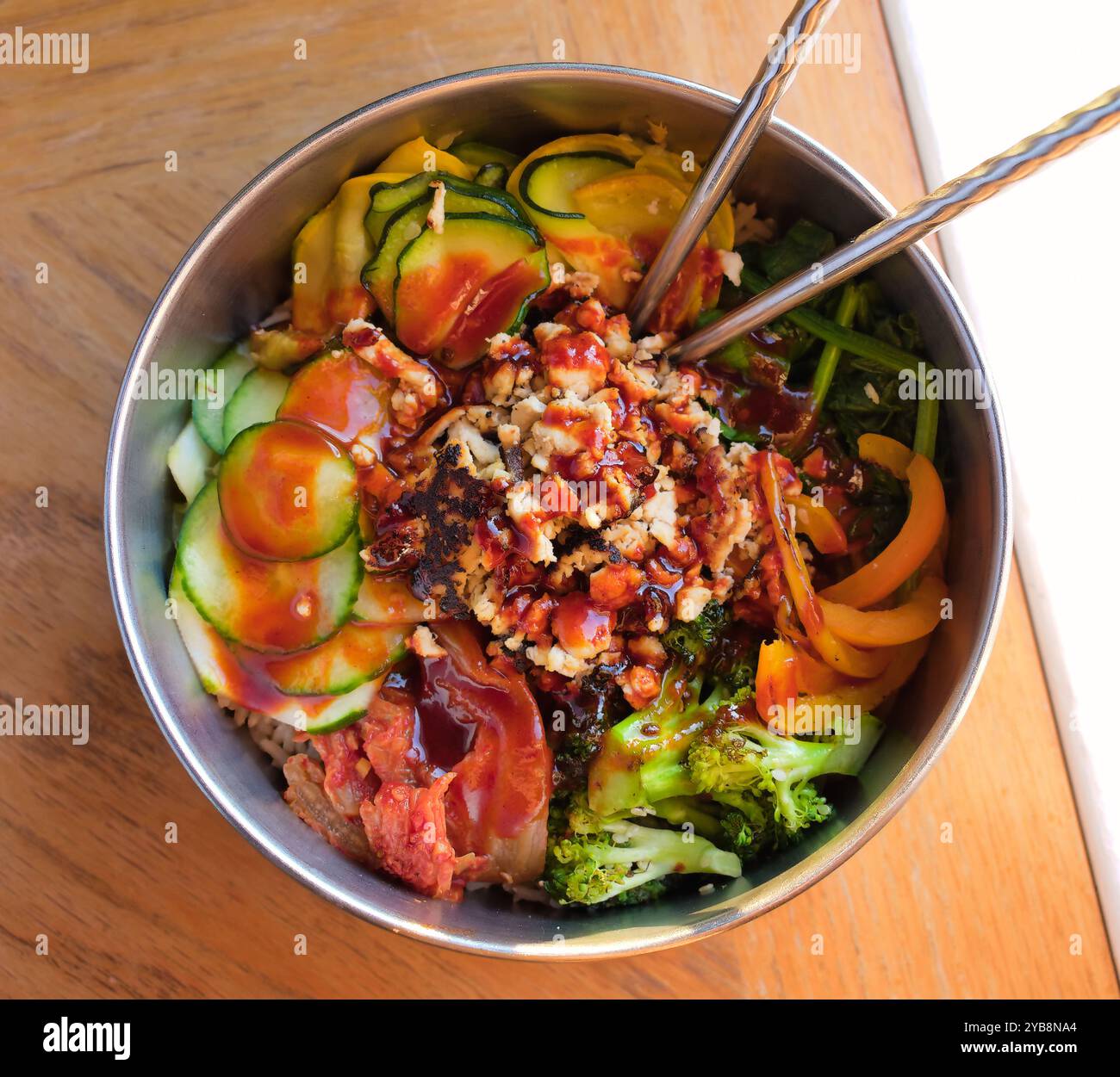 Bibimbap coreano fatto in casa speziato con tofu e verdure nella ciotola di metallo Foto Stock