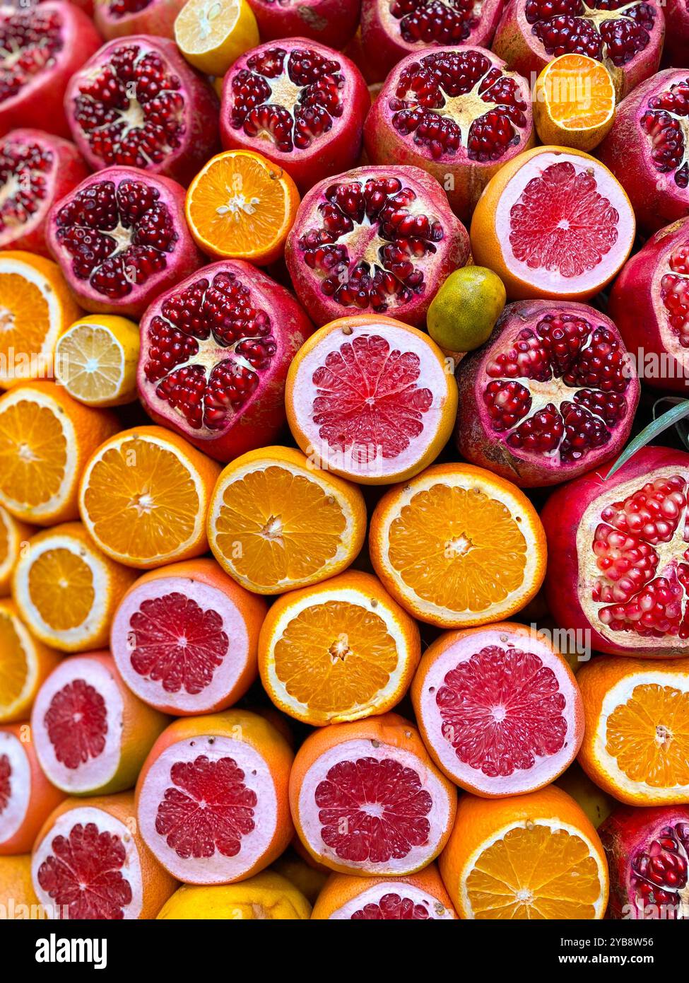 Agrumi colorati a fette. Disposizione di bellissime arance affettate, melograni con semi visti, pompelmi, mandarini pieni di vitamine Foto Stock
