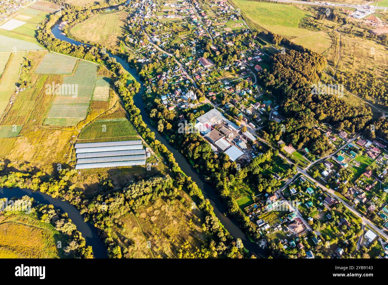 Vista aerea delle piantagioni agricole e del villaggio separati da un fiume Foto Stock