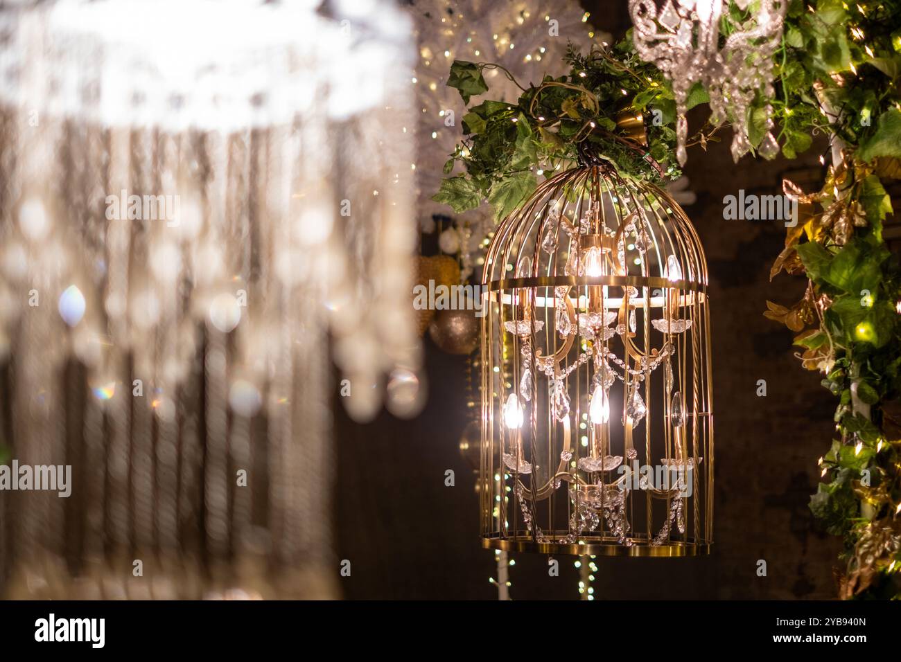 Lampadari dal design complesso sono appesi con grazia, circondati da decorazioni scintillanti che esaltano l'incantevole atmosfera. La creatura di illuminazione soffusa Foto Stock