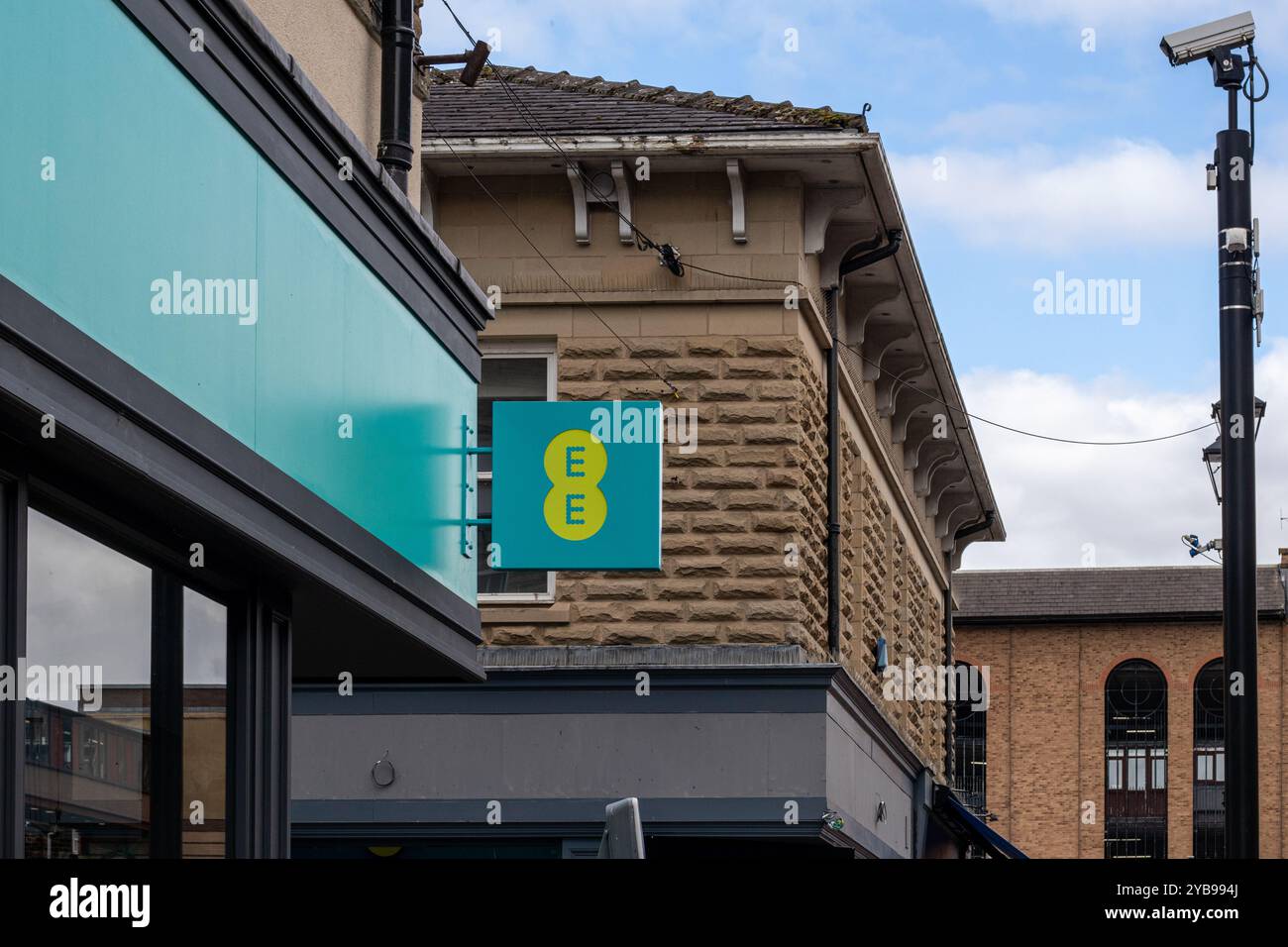 Vista ravvicinata di un negozio con un cartello con le lettere "EE" in un design moderno. L'edificio ha una facciata in pietra e si trova in una città Foto Stock