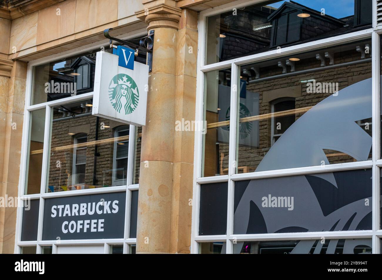 Esterno di una caffetteria Starbucks con logo e cartellonistica iconici. L'edificio presenta grandi finestre che mostrano un design moderno con un mix di pietra Foto Stock