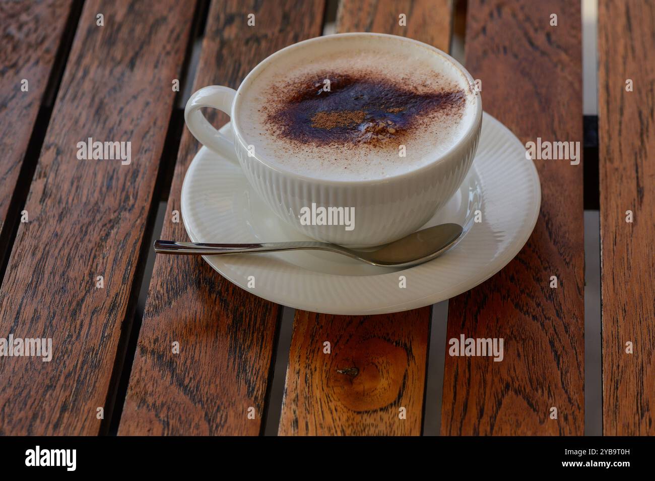 Assaporate una tazza di caffè cremoso, ricco di consistenza, circondato dal calore di un ambiente in legno illuminato dal sole, perfetto per rilassarsi e connettersi con la patatina fritta Foto Stock