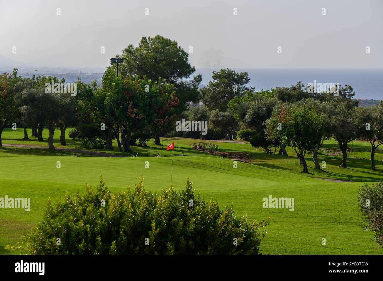 La luce del mattino proietta un caldo bagliore sull'ampio campo da golf, dove l'erba ben tenuta incontra le splendide vedute dell'oceano, creando un rifugio tranquillo per il golf Foto Stock